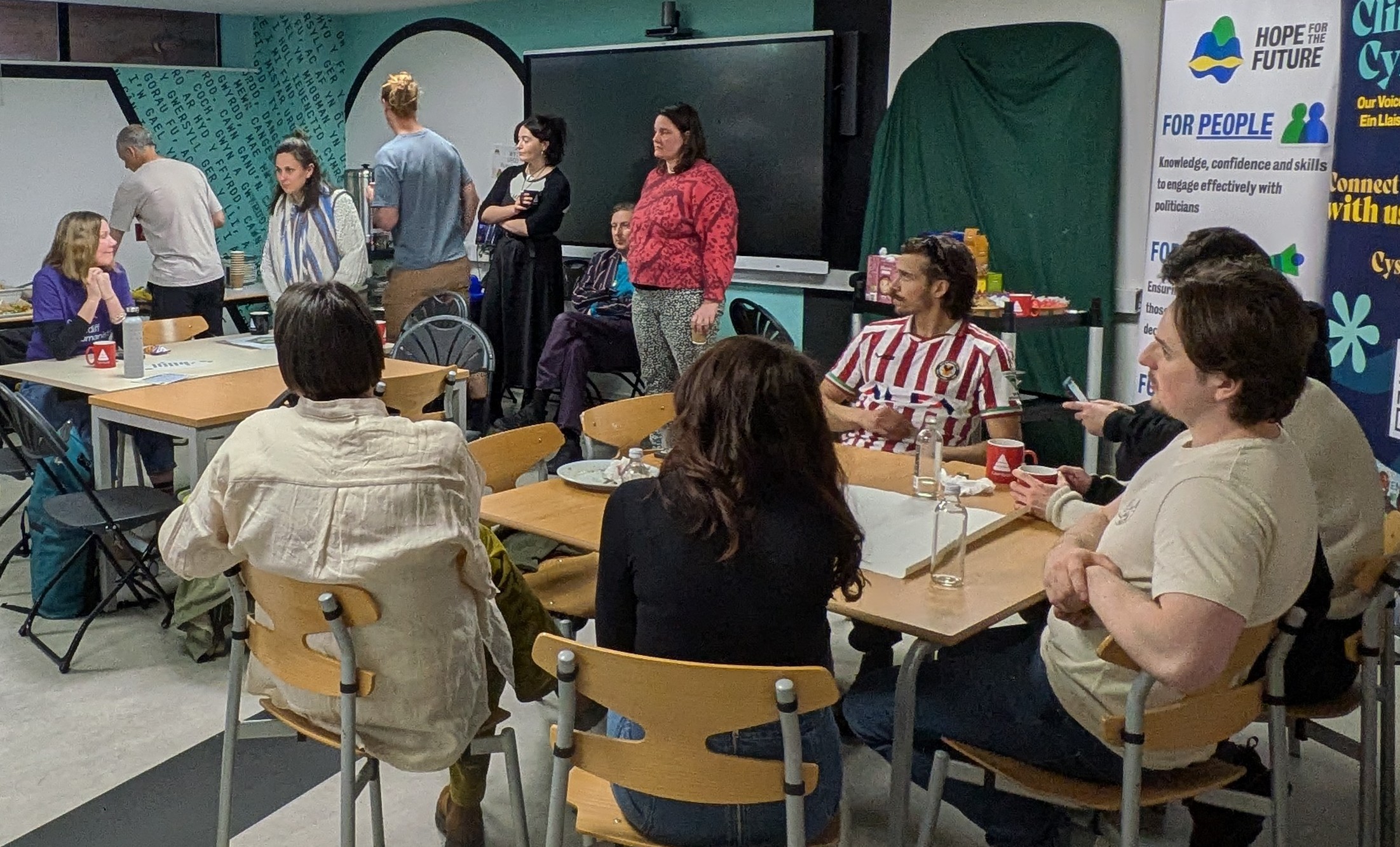13 people sitting around two tables inside